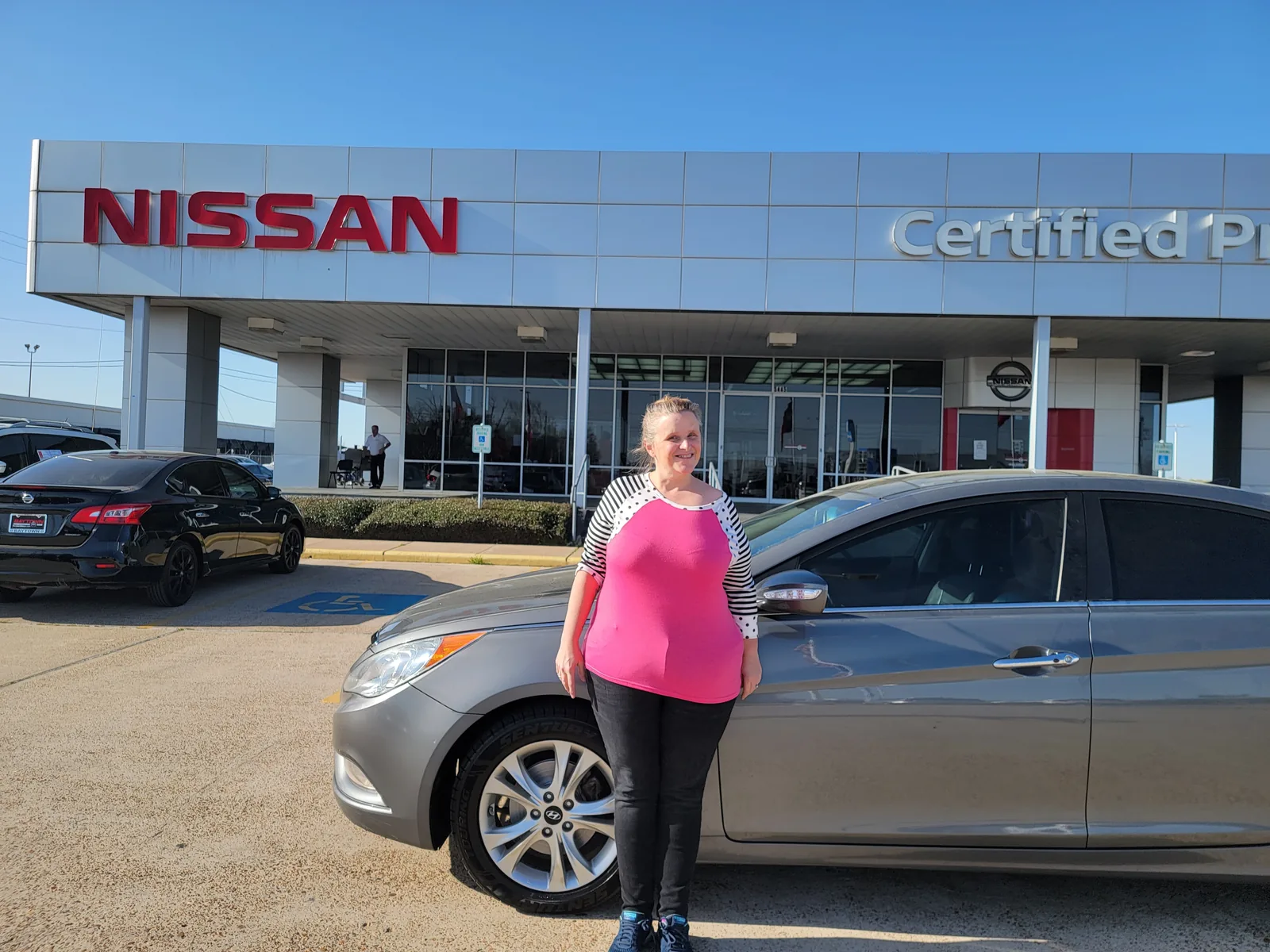 A customer beside the used car she was just approved for