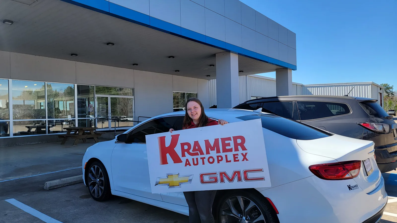 A customer with her newly purchased vehicle at the dealership