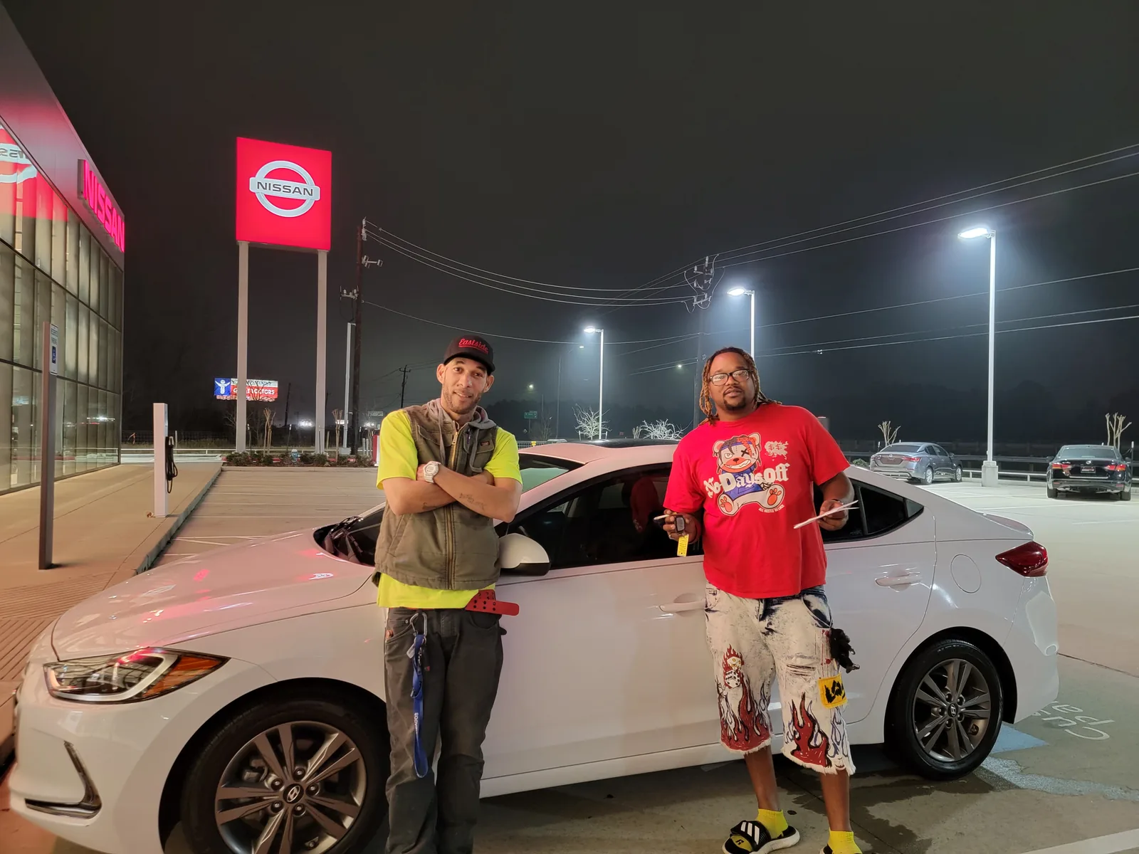 Two customers collecting their car on the lot after an evening approval
